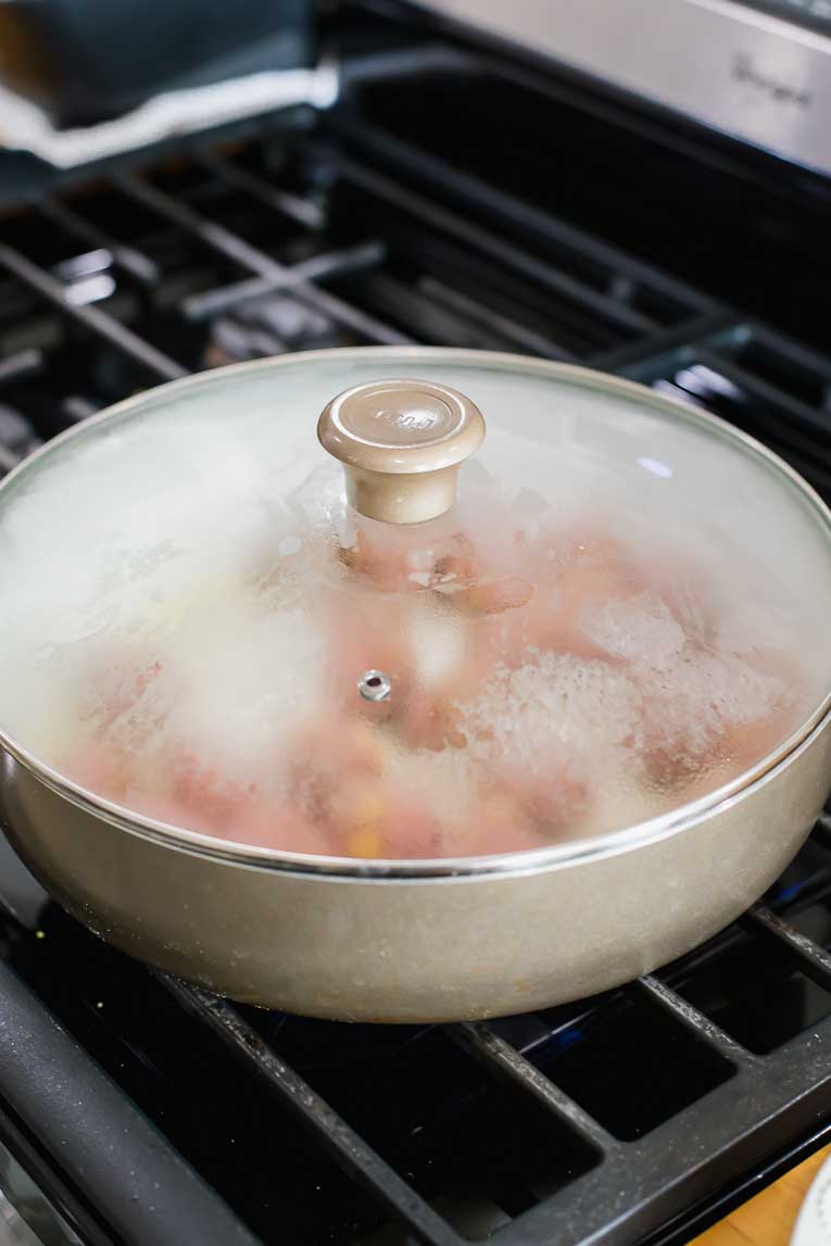 Turkey meatballs being cooked in a covered saucepan.