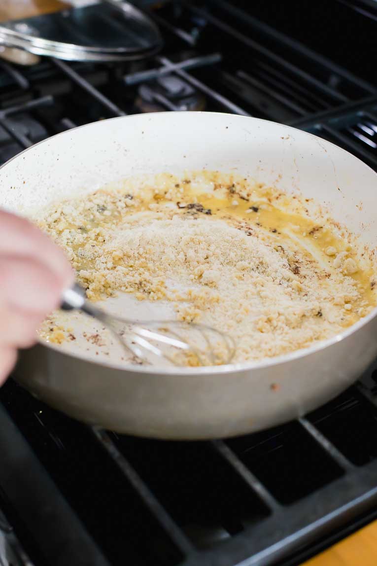 Butter and almond flour being whisked together in a saucepan.