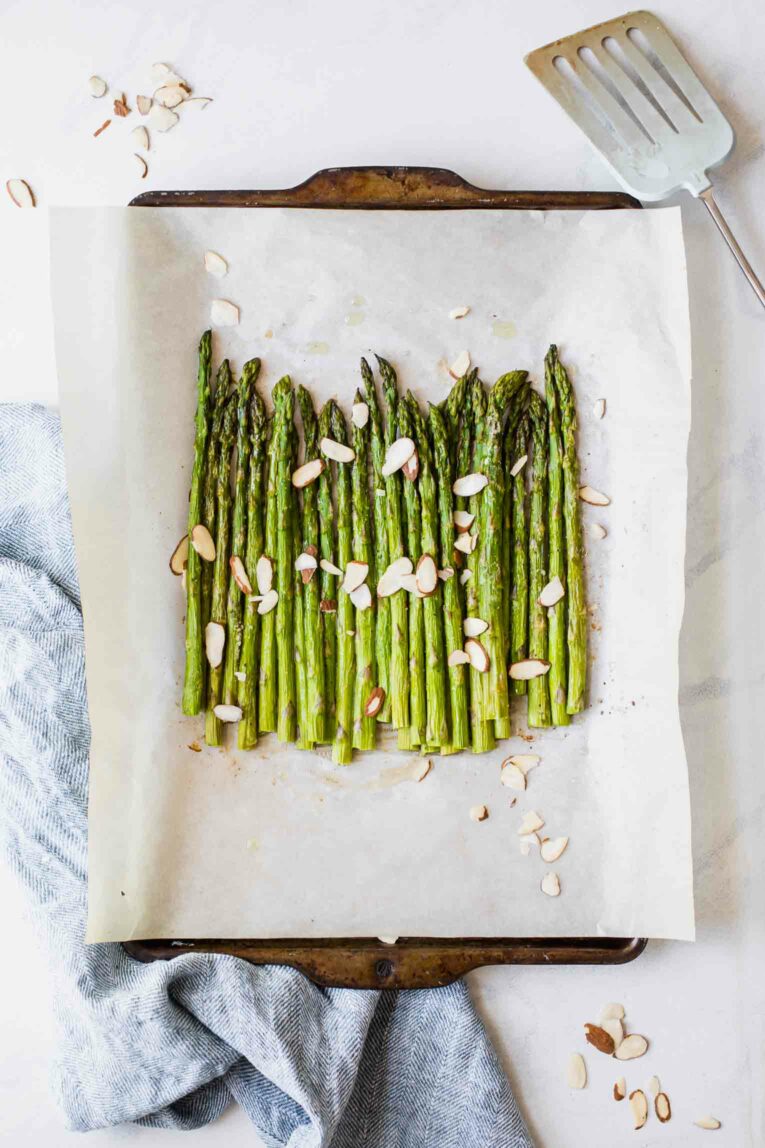 Roasted asparagus on a baking sheet with a blue napkin.