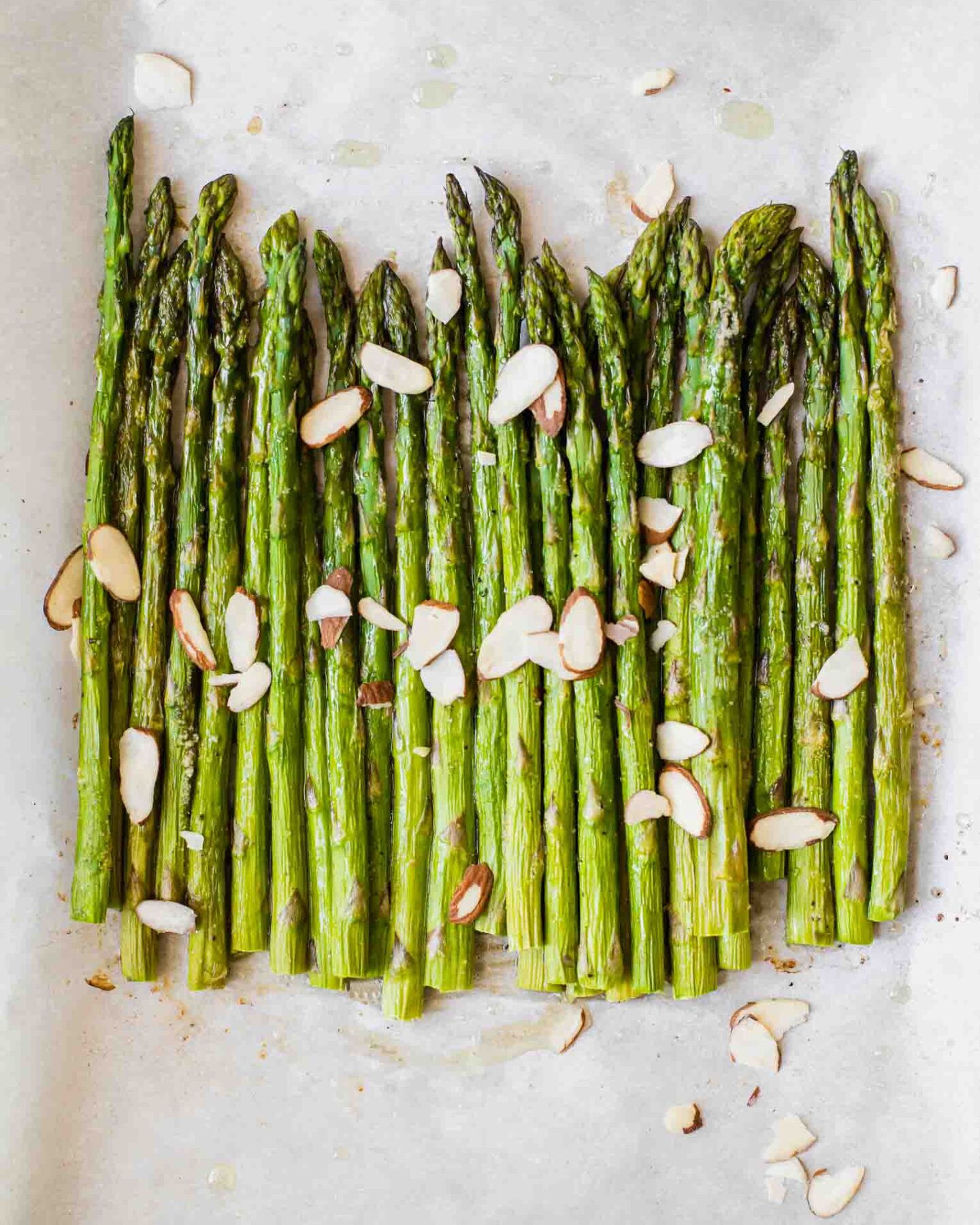 Close up of perfectly roasted asparagus on parchment paper.
