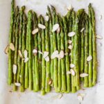 Close up of perfectly roasted asparagus on parchment paper.
