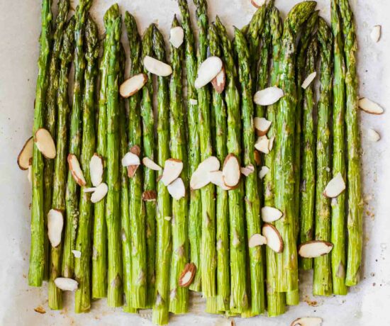 Close up of perfectly roasted asparagus on parchment paper.