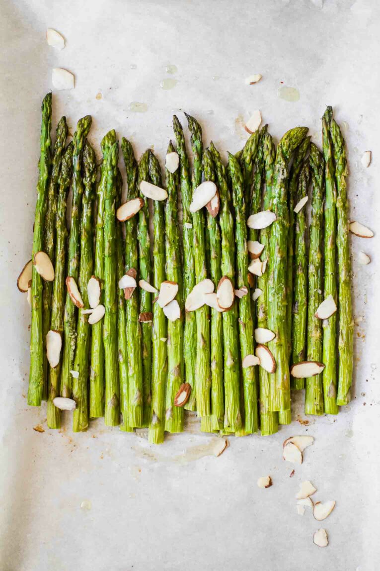 Close up of perfectly roasted asparagus on parchment paper.
