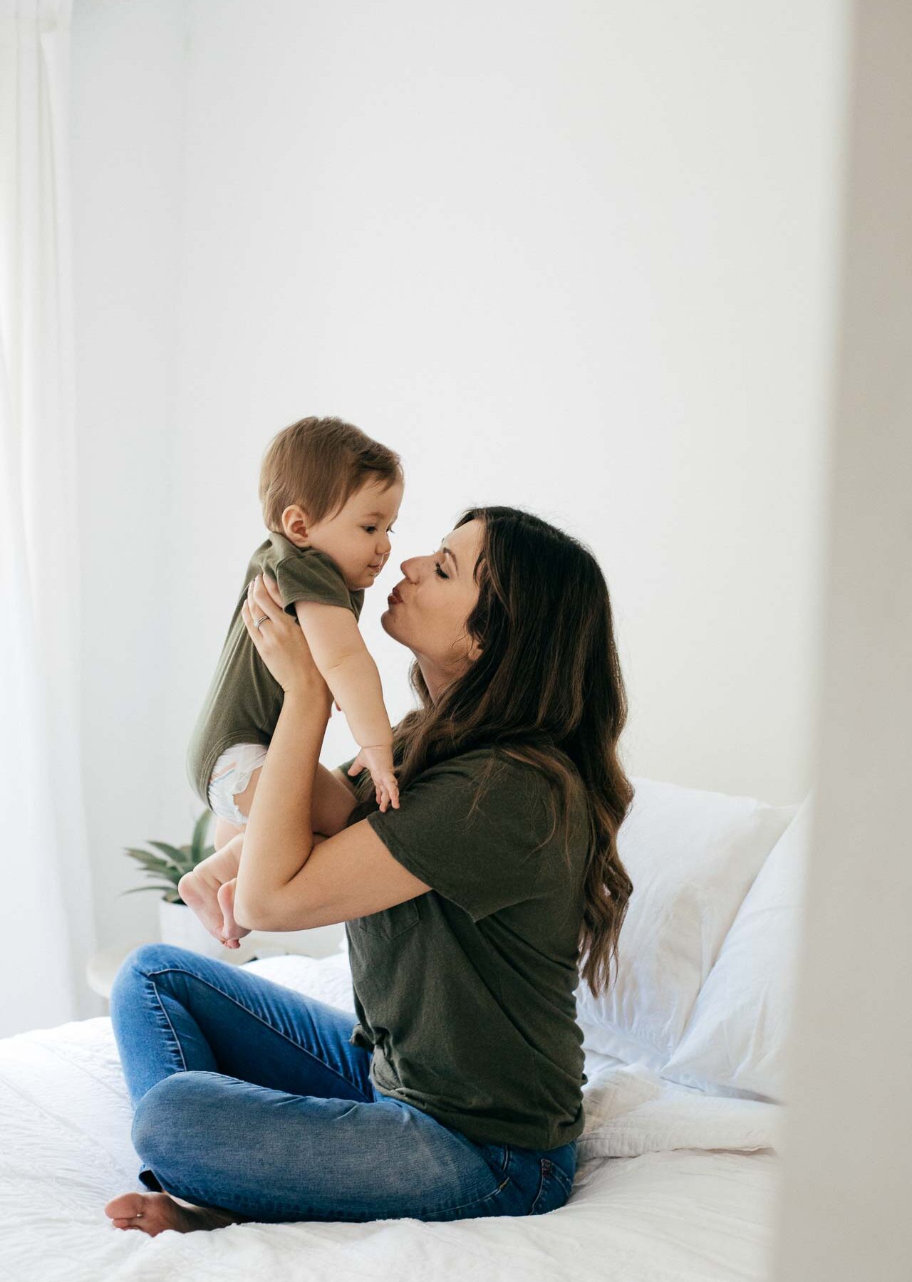 Mother holding baby up and kissing him.