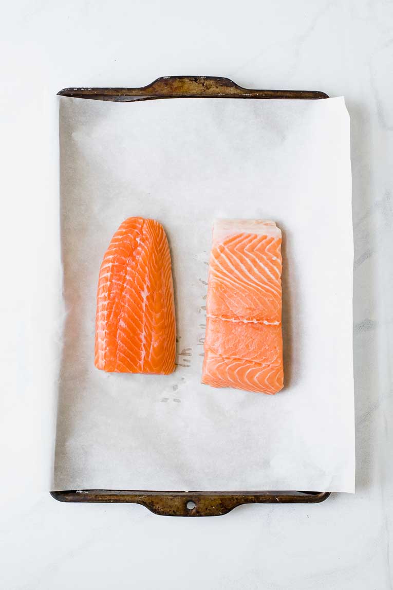 Two salmon filets on parchment paper on a baking sheet.