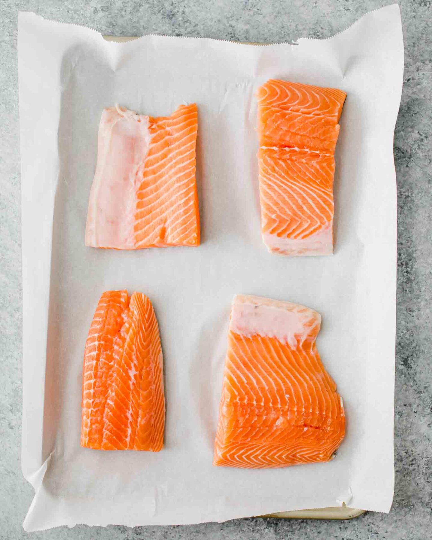 Four salmon filets on parchment paper.