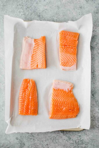 Four salmon filets on parchment paper.