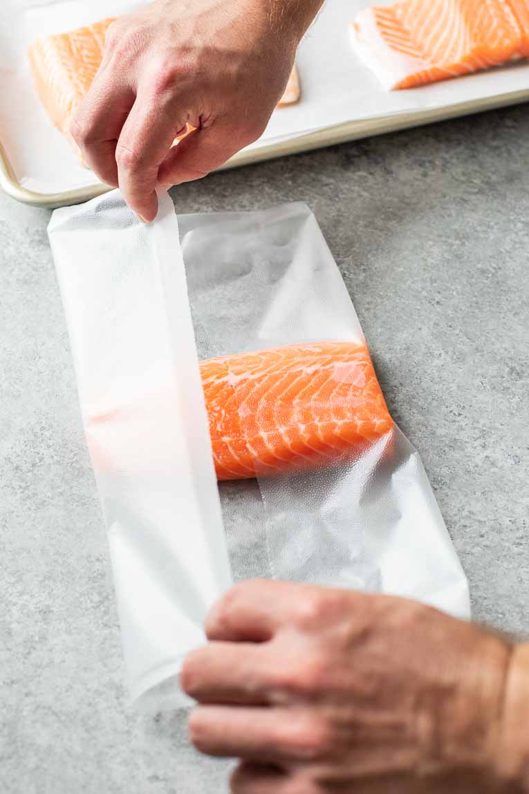 Folding plastic wrap over salmon filet.