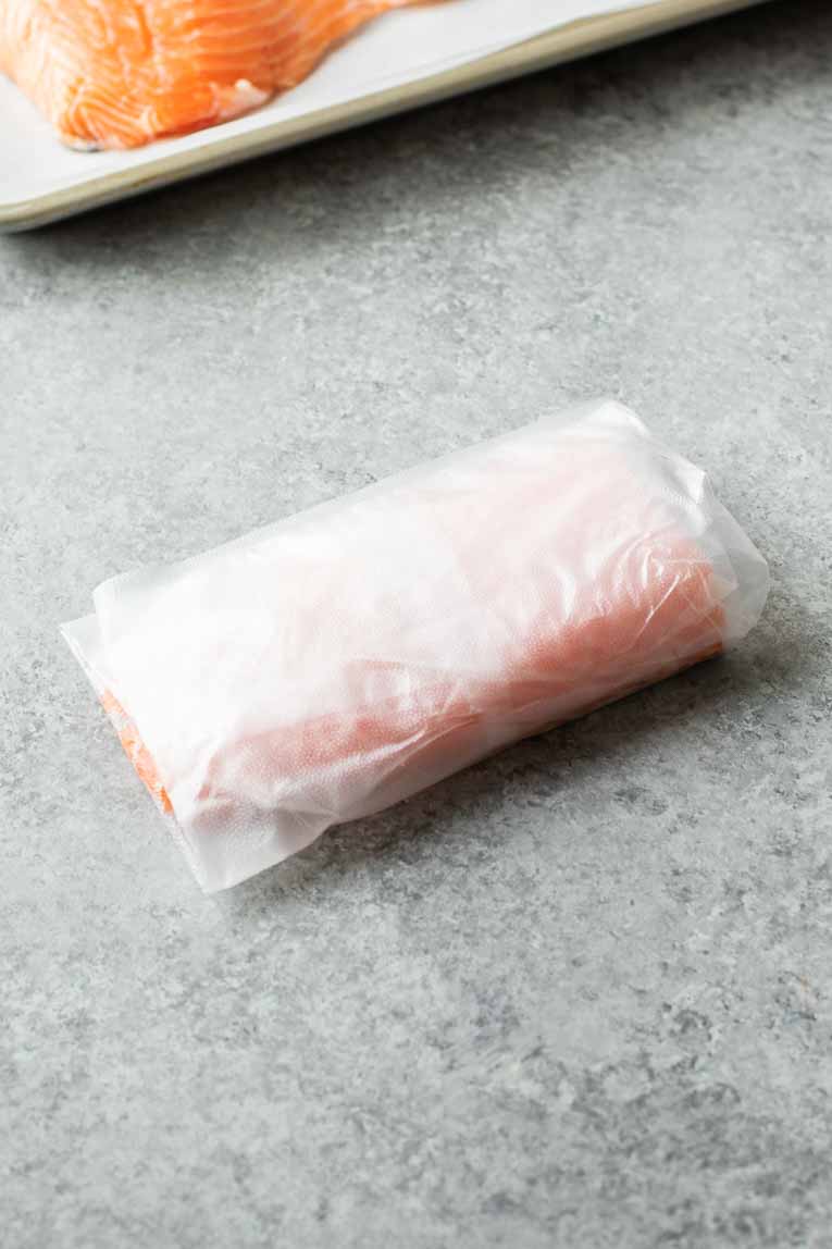 Salmon filet wrapped in plastic wrap for freezing.