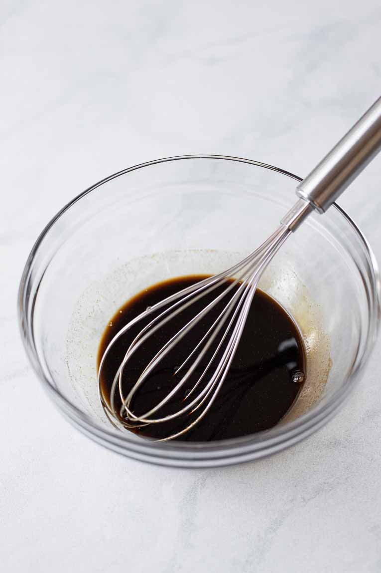 Asian sauce being whisked together in a glass bowl.