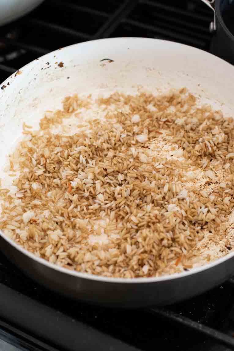 Fried rice being cooked with soy sauce in a pan.