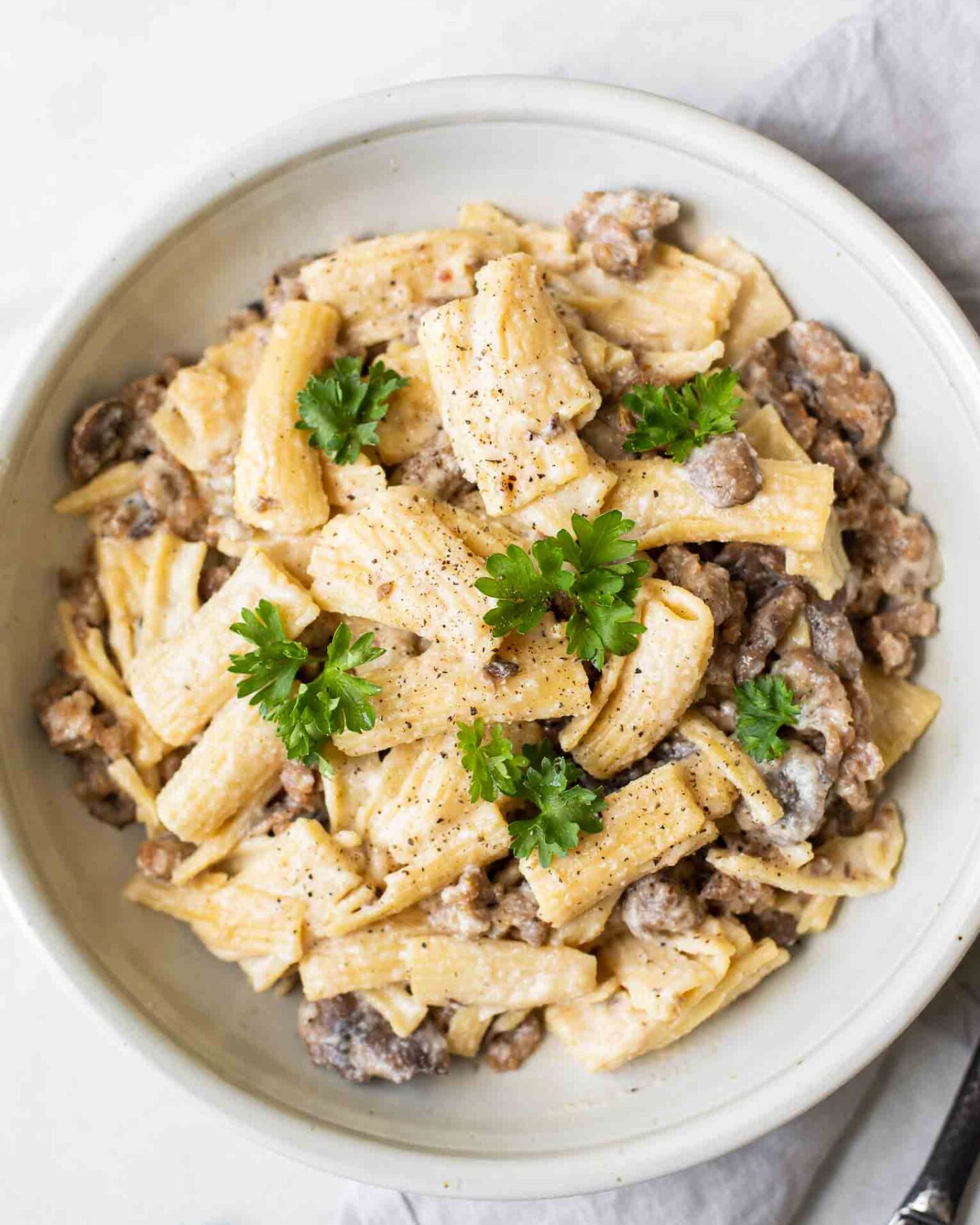 Creamy Mushroom Sausage Rigatoni topped with fresh parsley in a white bowl.