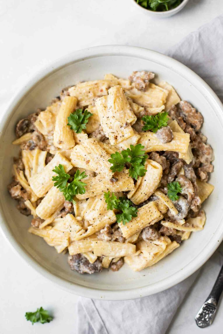 Creamy Mushroom Sausage Rigatoni topped with fresh parsley in a white bowl.