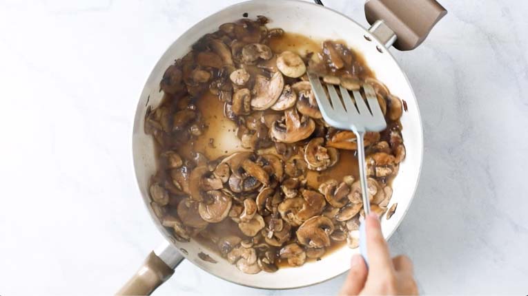 Mushrooms being sautéed in a pan.