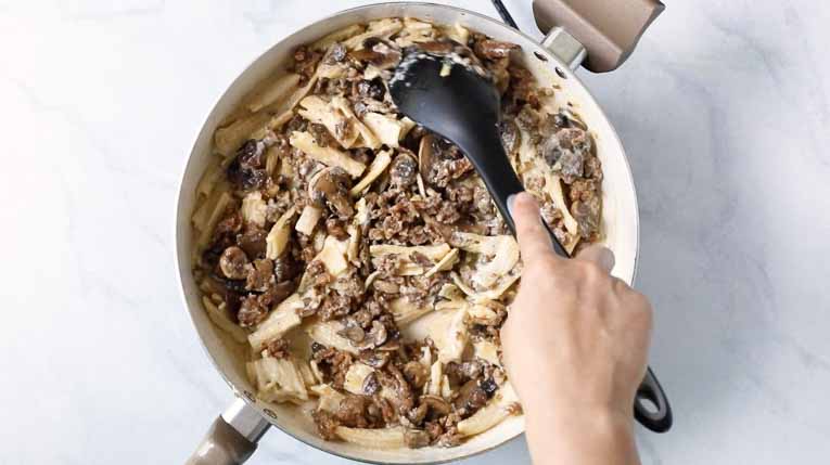 Creamy Mushroom Sausage Rigatoni being heated up in a white pan.