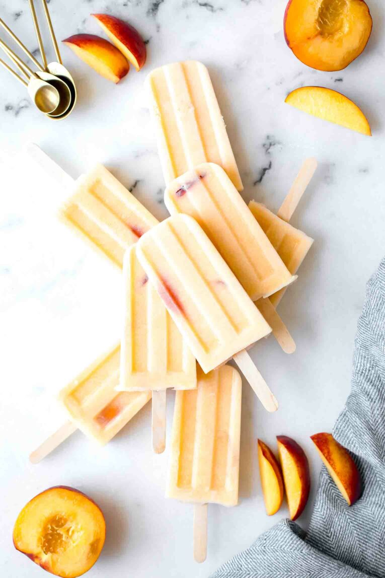 Top shot of Homemade Creamy Peach Popsicles on a marble board.