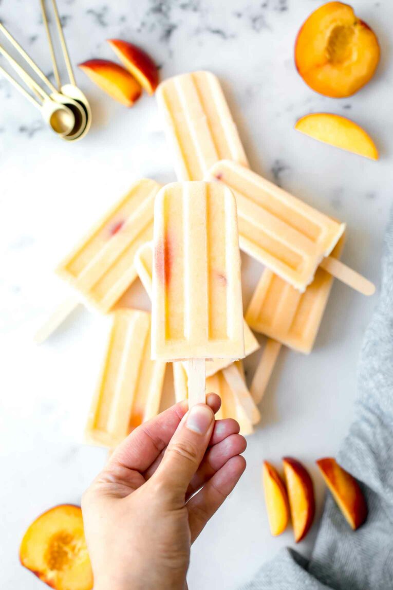 Hand holding a creamy peach popsicle.