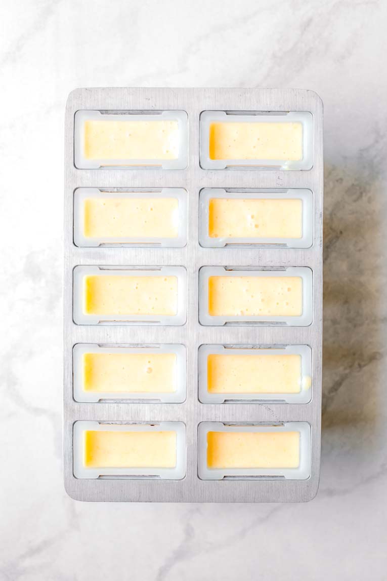 Peach popsicle mix poured into a popsicle mold.