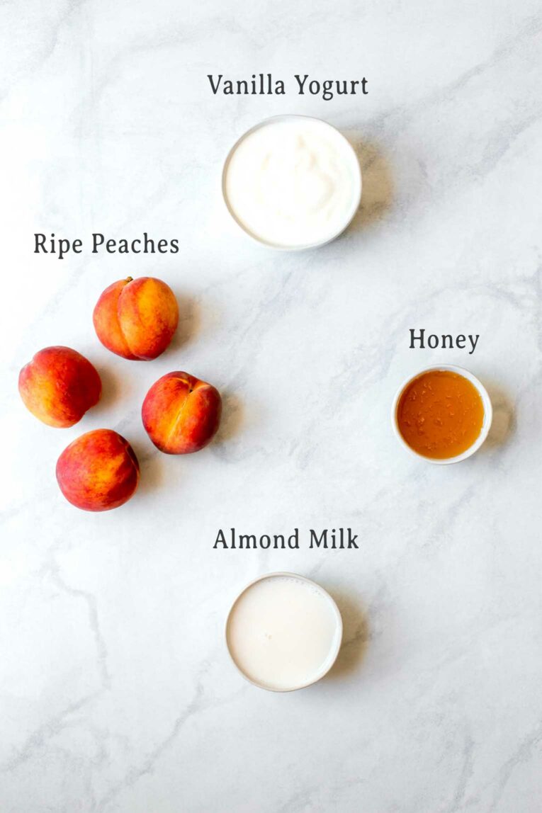 Ingredients for Homemade Creamy Peach Popsicles on a marble board.