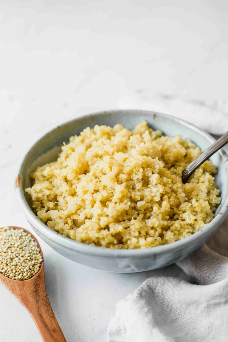 Angled shot of cooked quinoa in a blue blow with a fork.