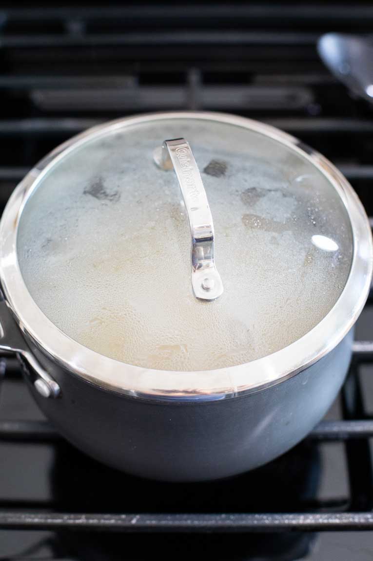 Covered pot of cooking quinoa.