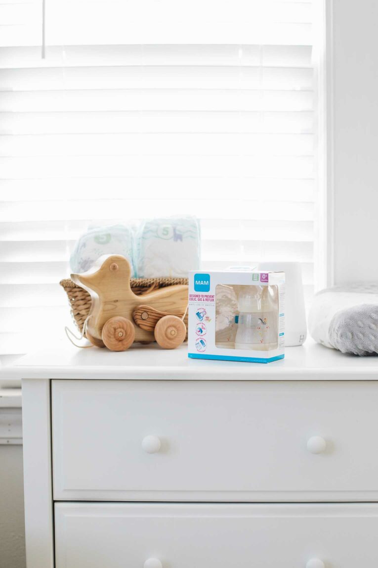 Baby nursery dresser with MAM baby bottles on top.