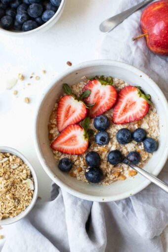 Close up of oatmeal topped with strawberries and blueberries.