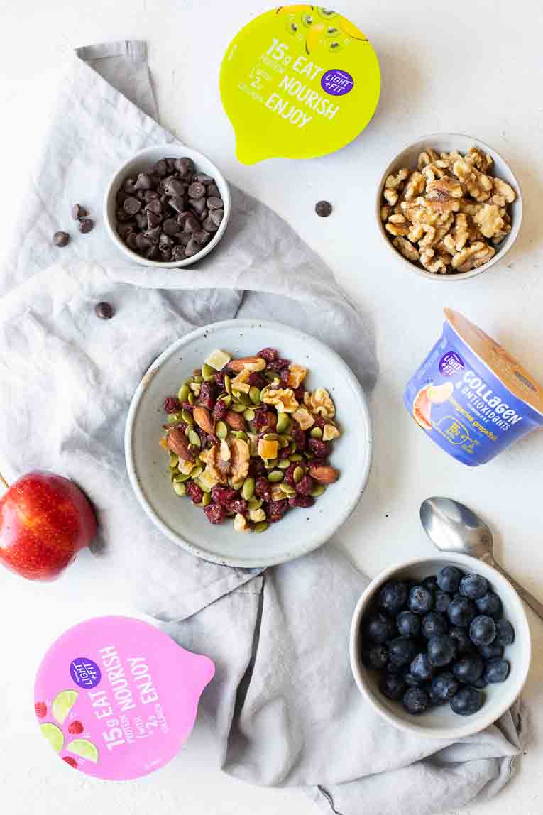 Walnuts, chocolate chips, trail mix, blueberries, apple, and light + fit yogurt cups.
