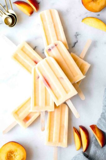 Top shot of Homemade Creamy Peach Popsicles on a marble board.