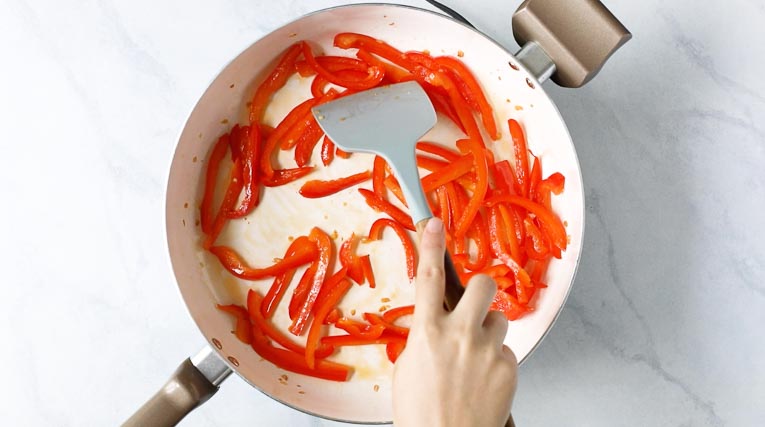 Peppers being stir fried in a pan.