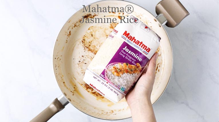 Hand holding Mahatma Jasmine Rice over a pan.