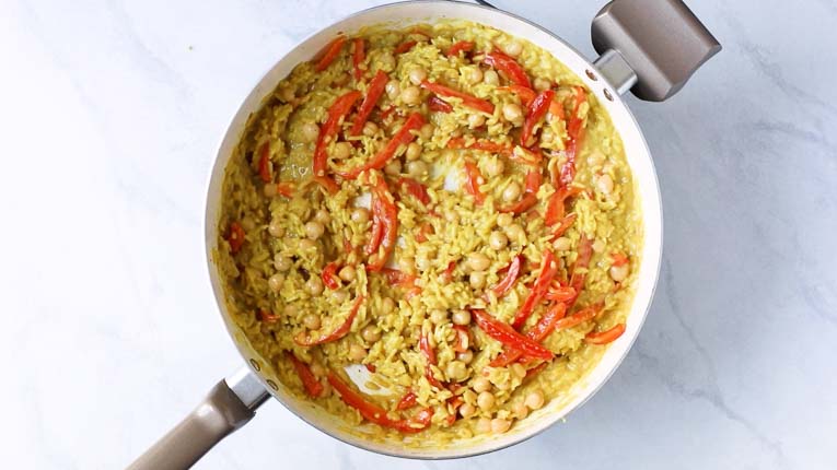 Rice and chickpea curry in a pan with red peppers.