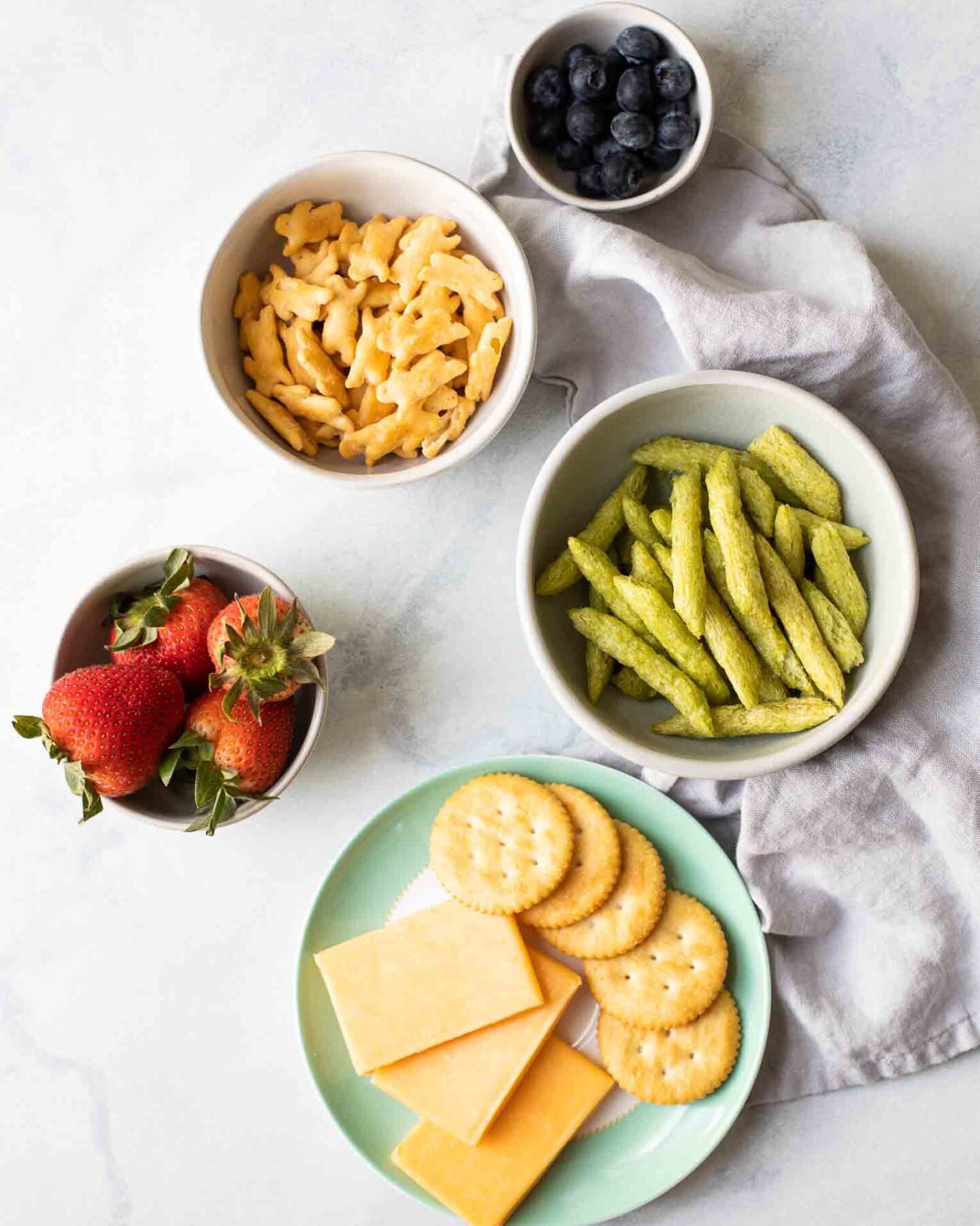 Bowls full of healthy toddler snacks on a marble board.