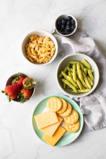 Bowls full of healthy toddler snacks on a marble board.