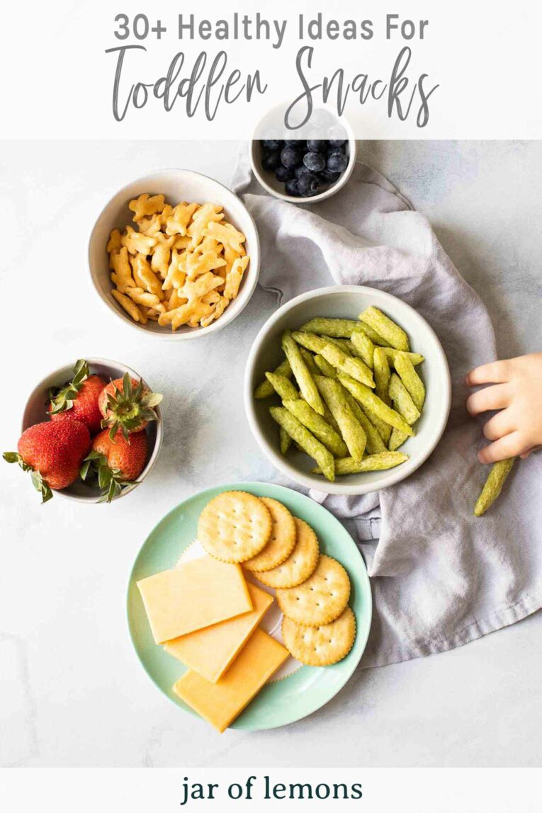 Toddler hand reaching for healthy snacks on a marble countertop.