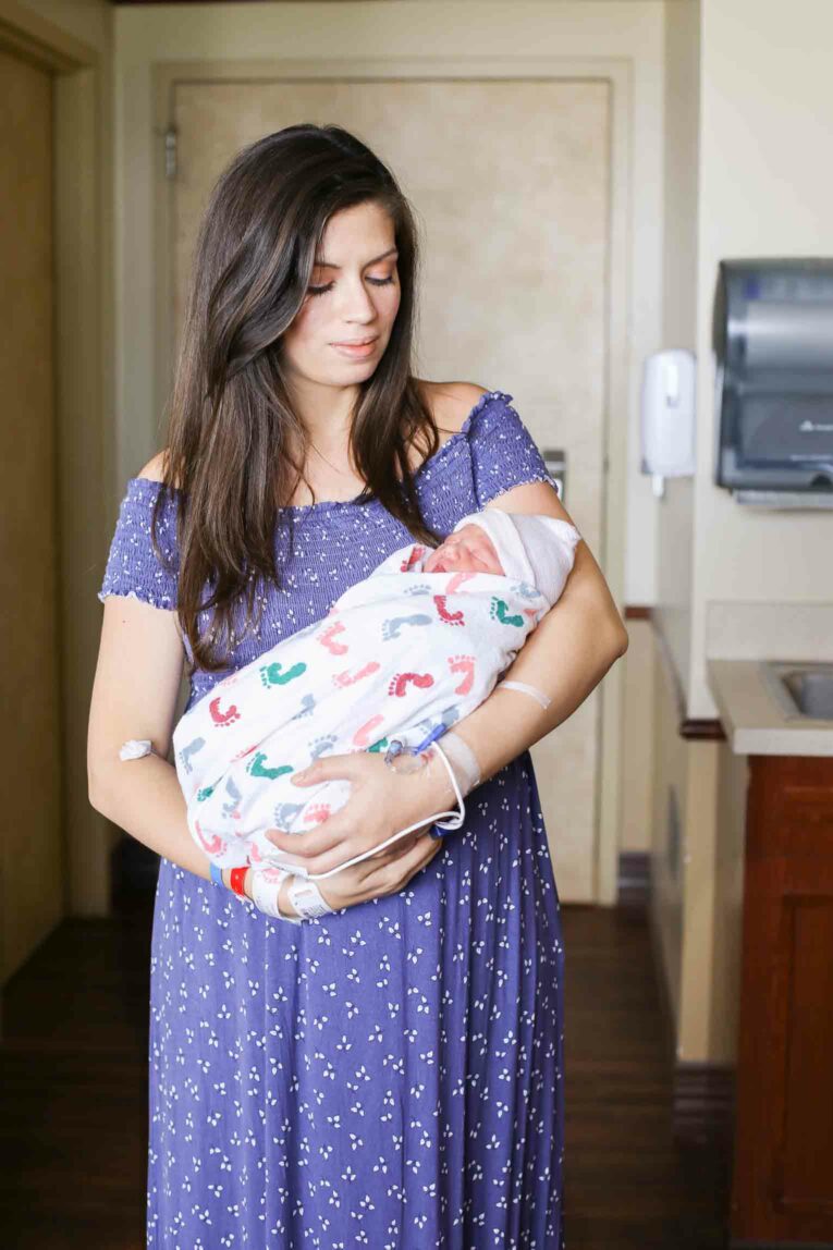 New mom holding her newborn baby in a hospital room.