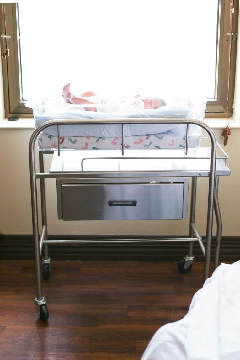 Newborn baby by the window in a hospital room.