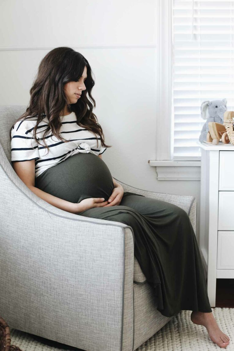 Pregnant mother sitting on chair in nursery.