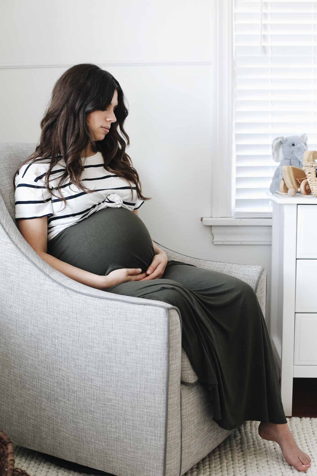 Pregnant mother sitting on chair in nursery.