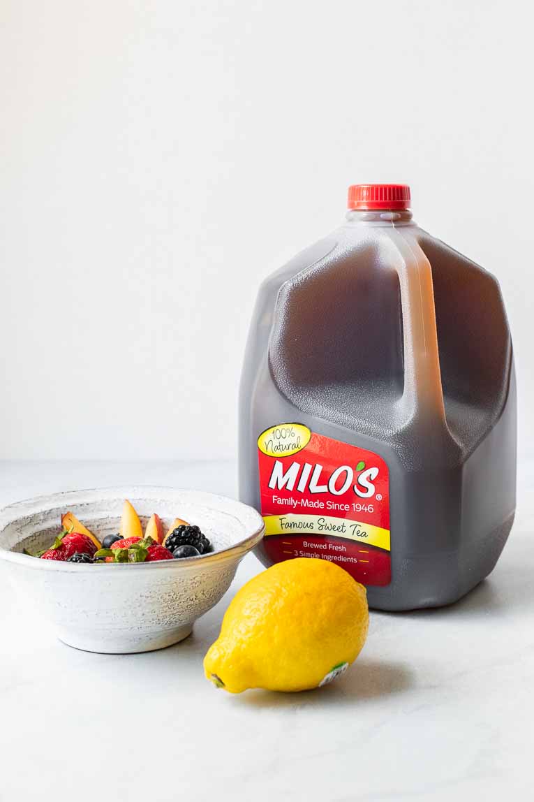 Fruit, Lemon, and Milo's Sweet Tea jug on a marble board.
