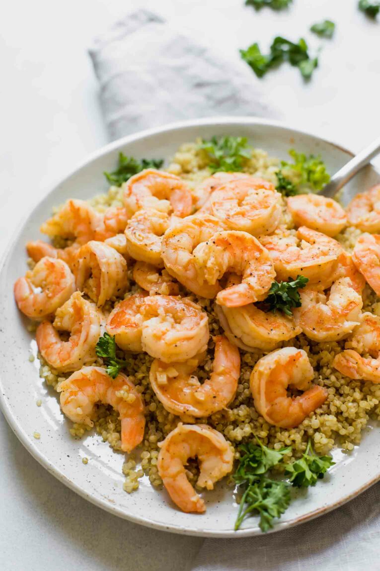 Angled shot of Easy Lemon Garlic Shrimp recipe over quinoa with parsley.