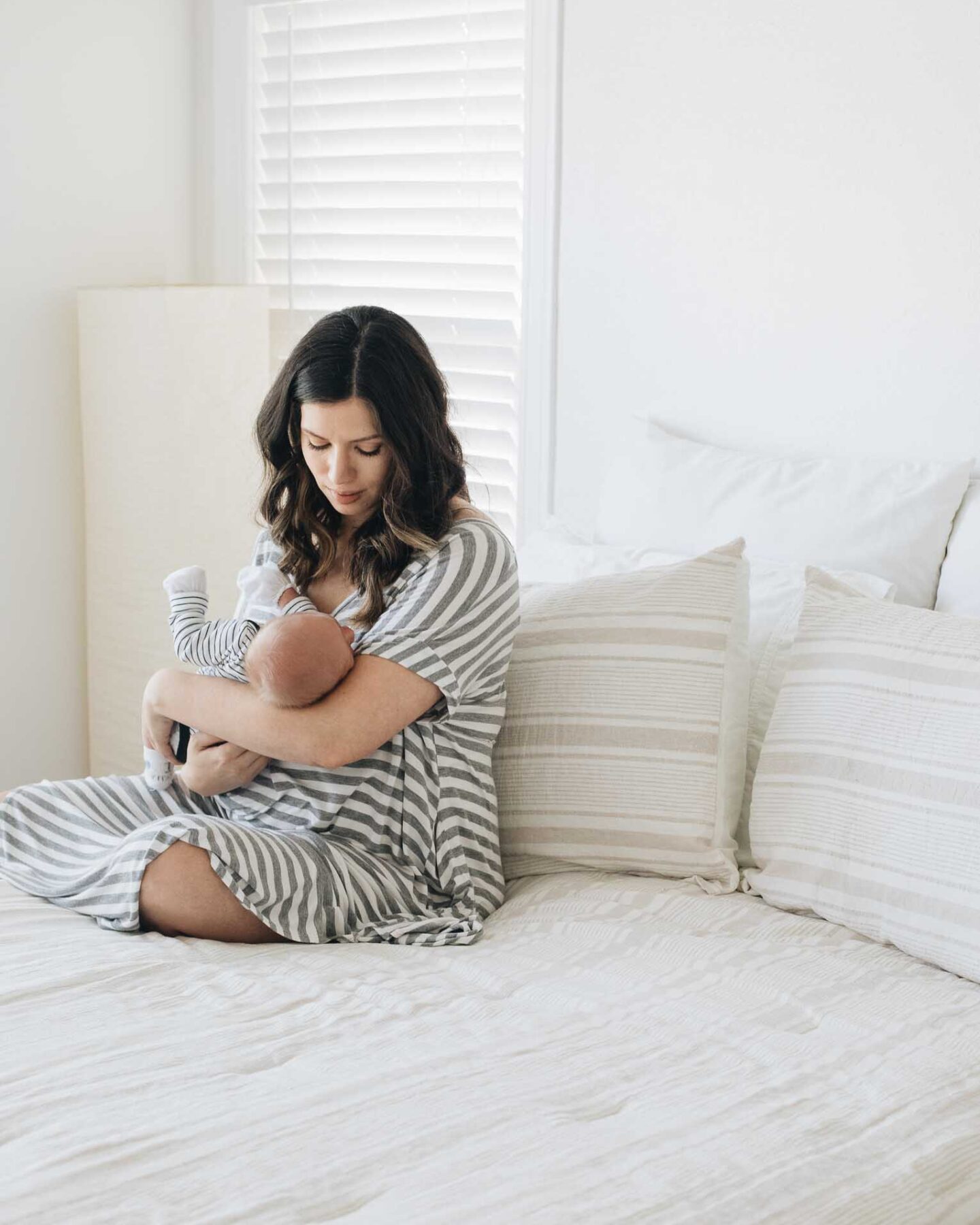 Angled shot of mother on bed holding her newborn baby.