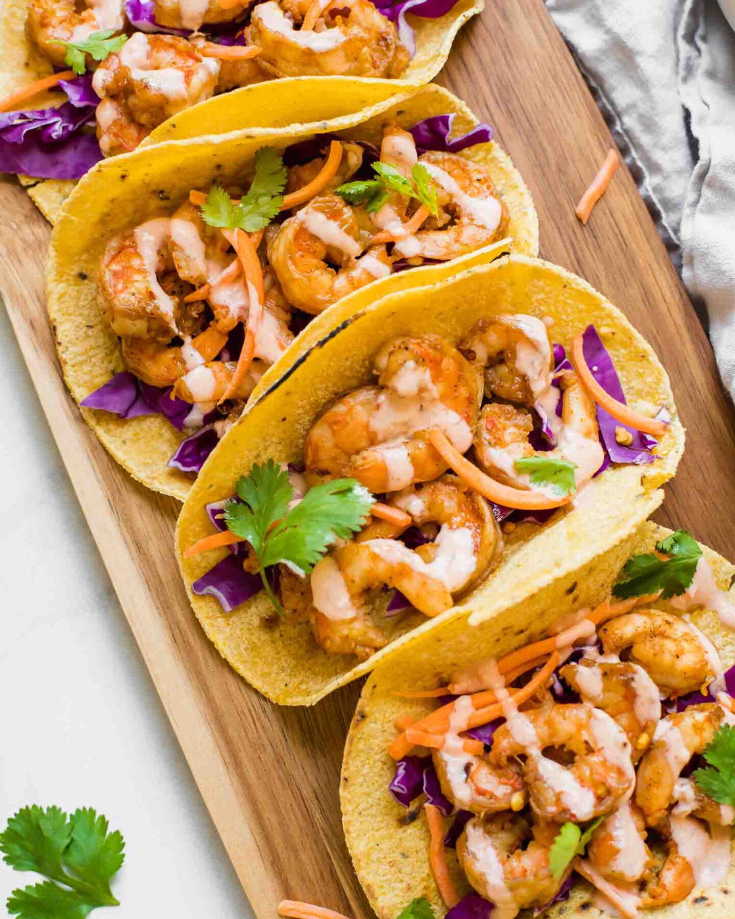 Top shot of Sriracha Lime Shrimp Tacos on a brown cutting board.