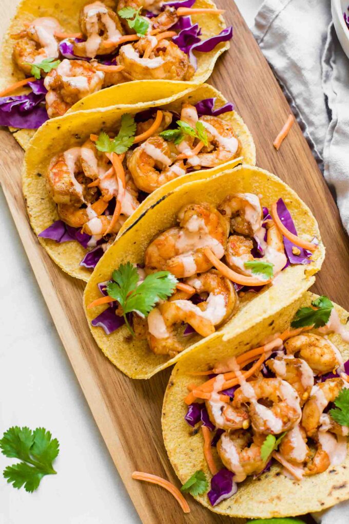 Top shot of Sriracha Lime Shrimp Tacos on a brown cutting board.