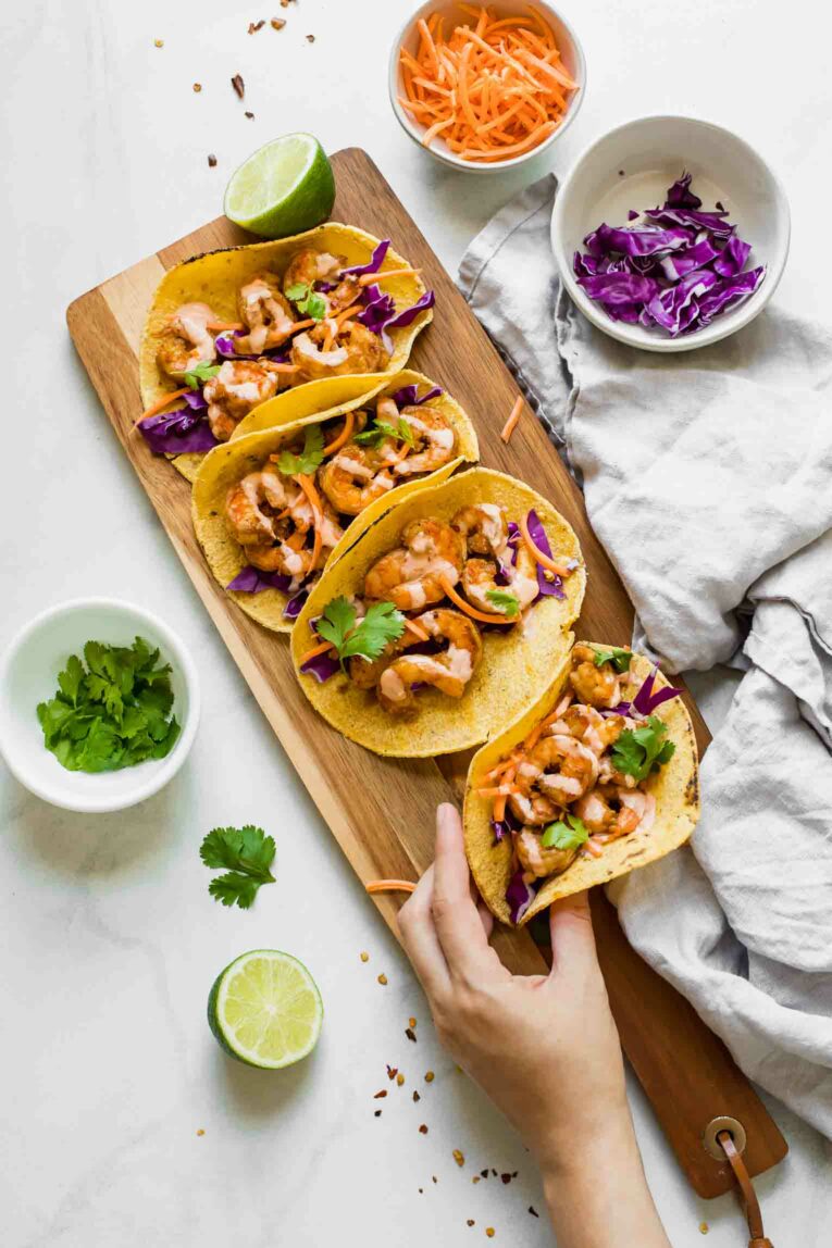 Hand lifting a shrimp taco off of a cutting board.