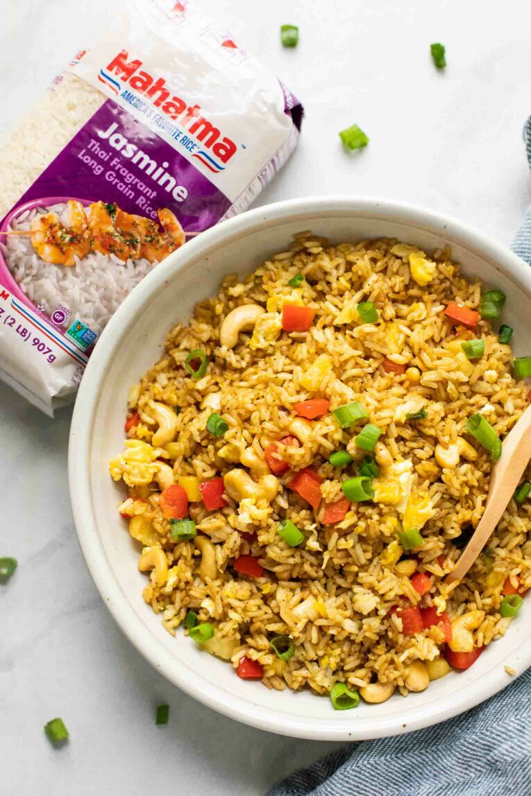 Top shot of Thai Pineapple Fried Rice in a white bowl next to Mahatma Jasmine Rice.