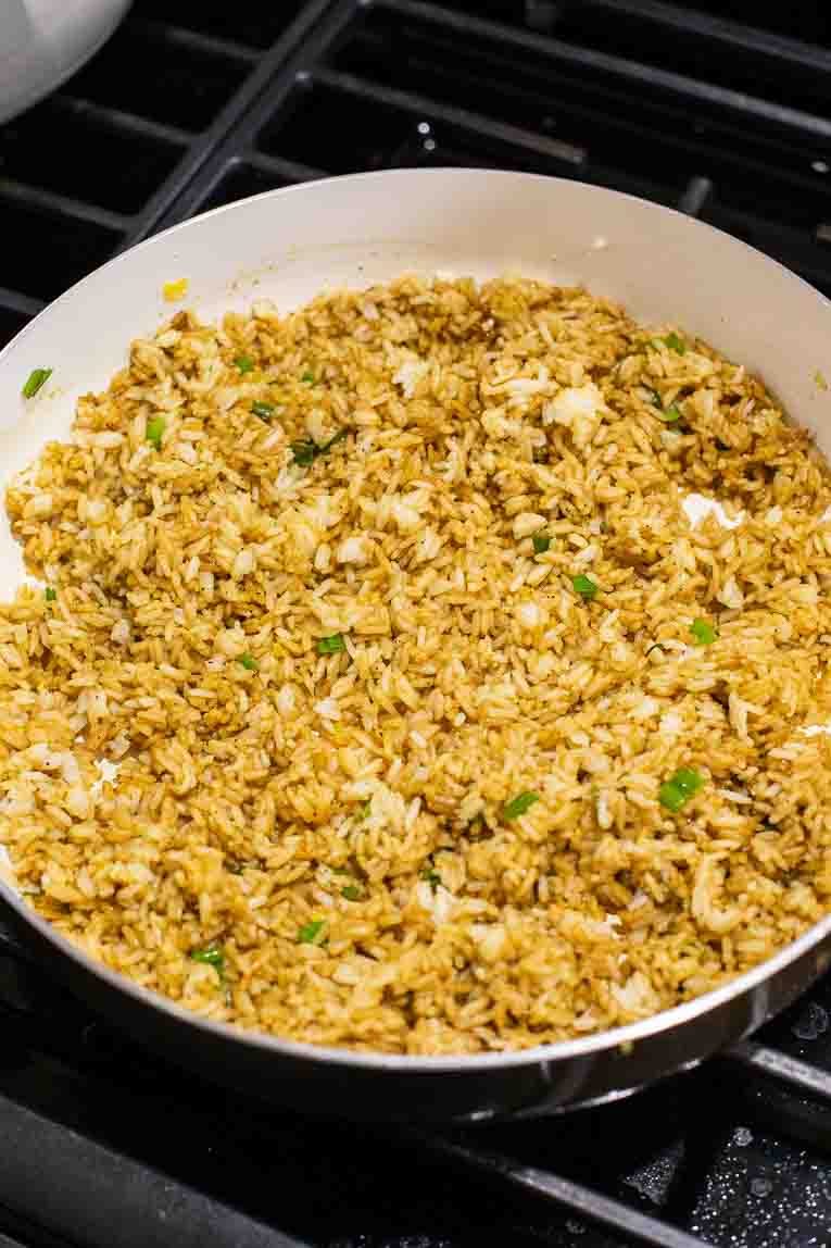 Jasmine rice being stir-fried with soy sauce and curry.