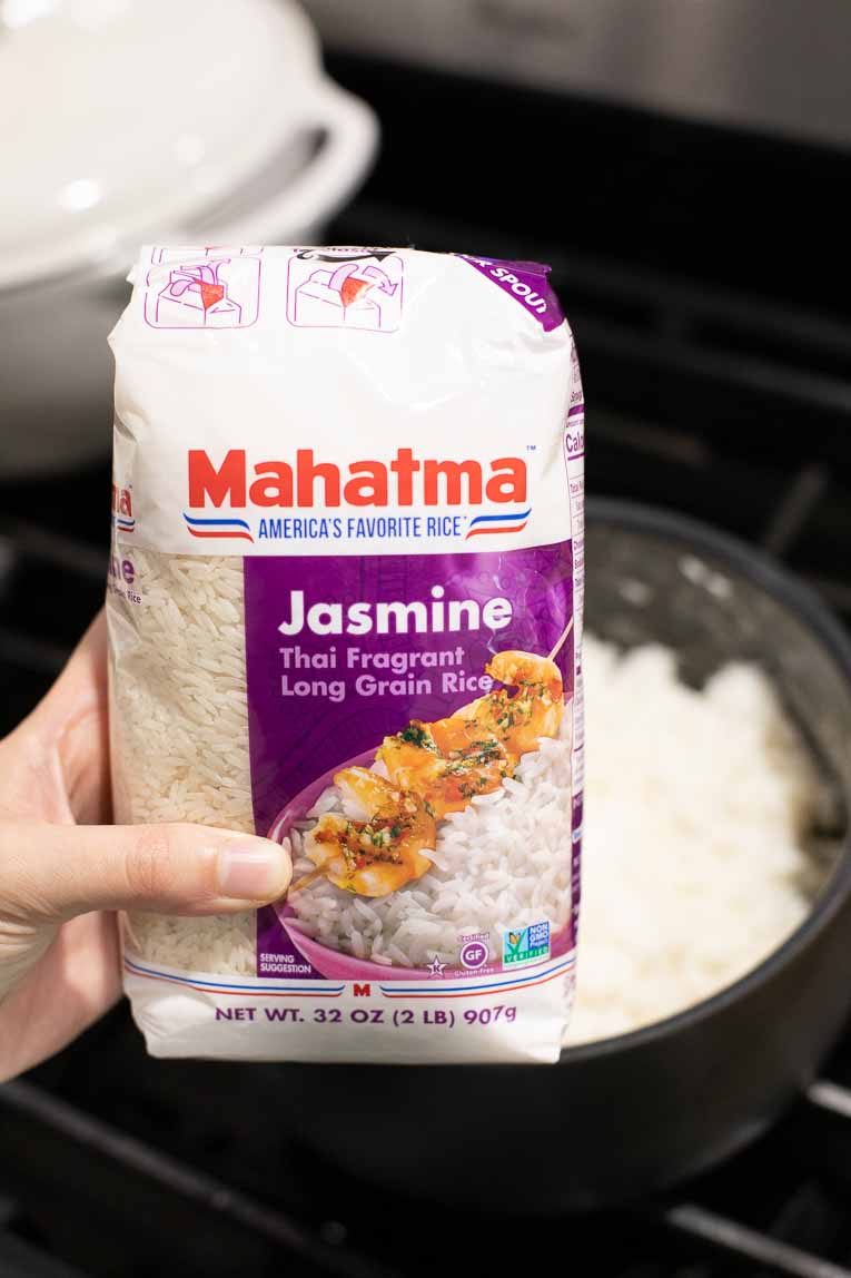 Hand holding Mahatma Jasmine Rice next to stove top.