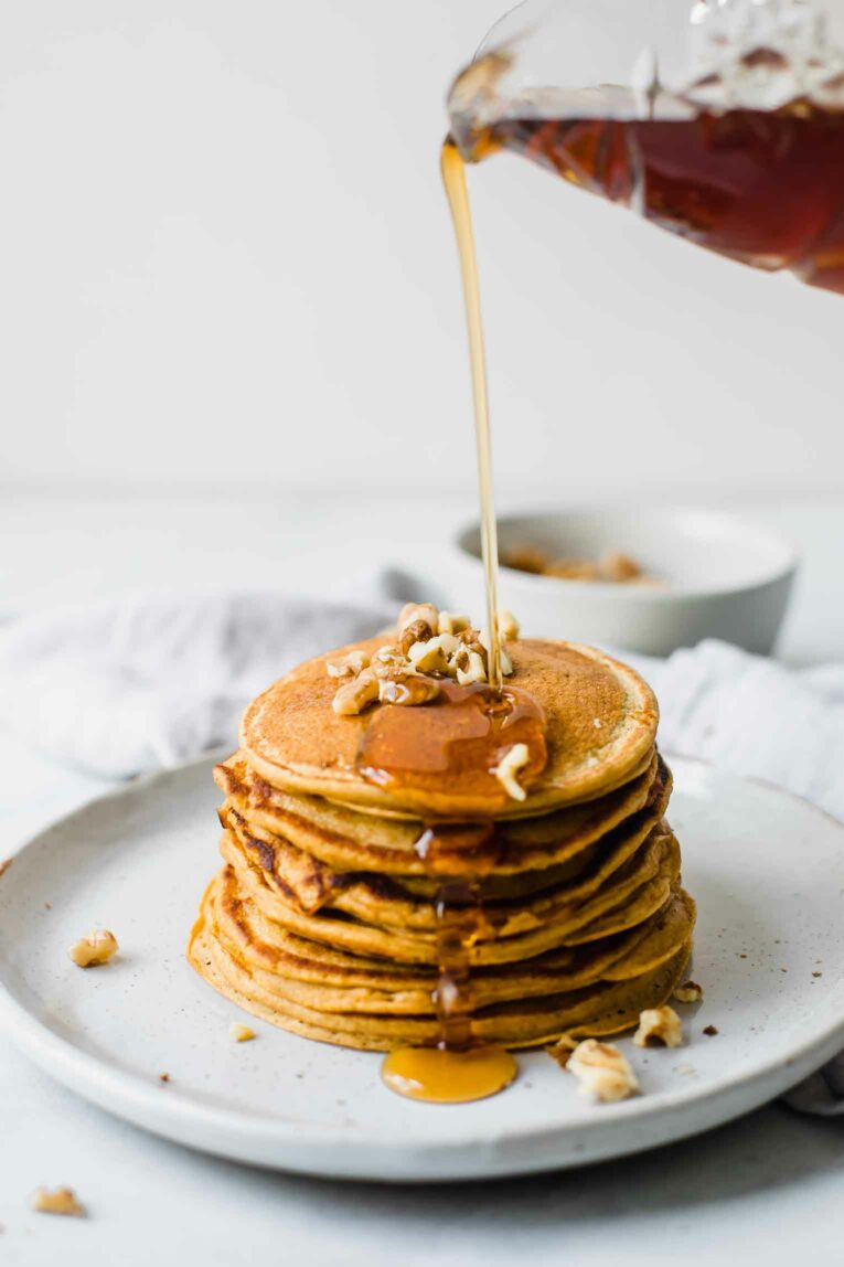 Stack of sweet potato pancakes with syrup pouring over them.