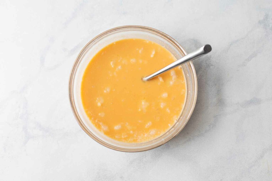 Liquid pancake ingredients in a glass mixing bowl.